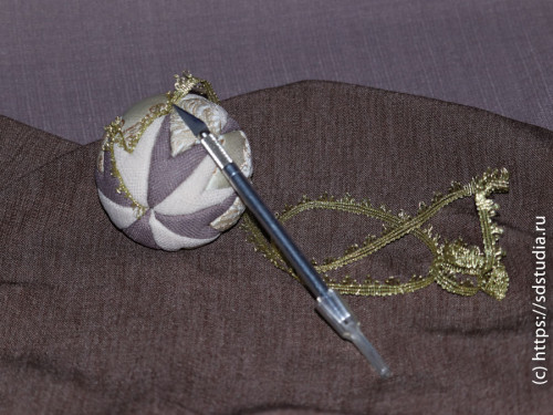 Заправляем ткань в прорези на шаре тупой стороной лезвия макетного ножа